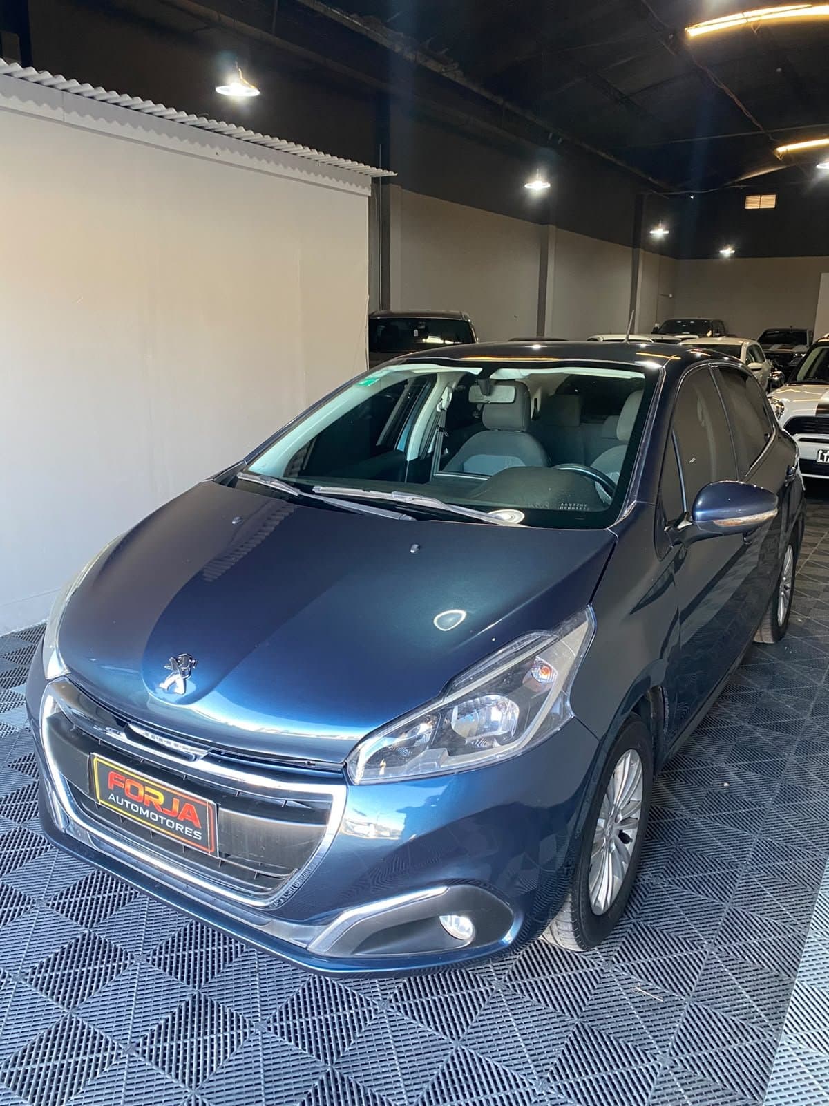 Peugeot 208 azul, frente tres cuartos, en el showroom