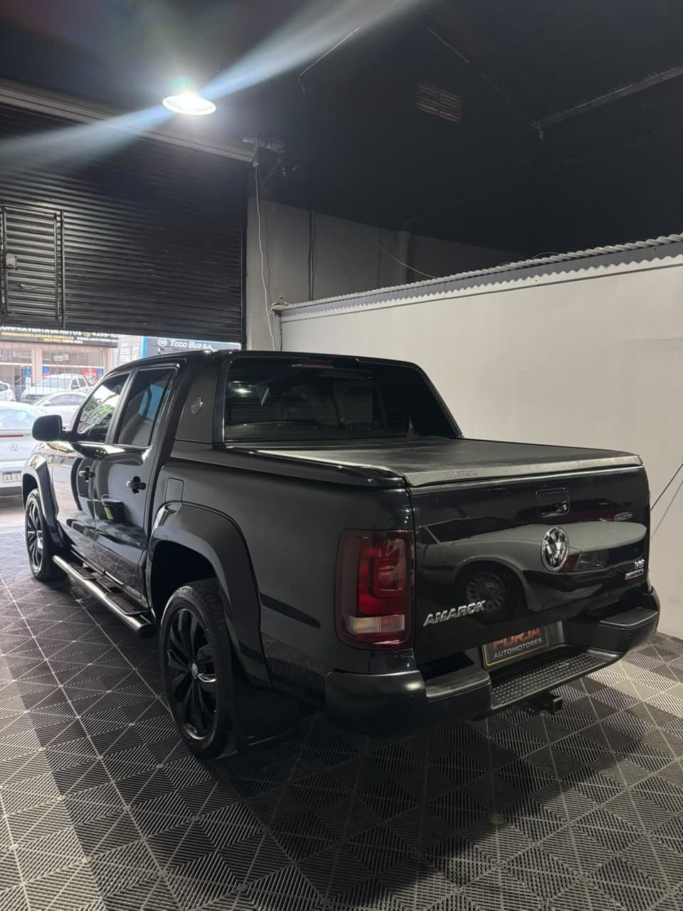Amarok negra, tres cuartos de atrás, con estribos y llantas negras