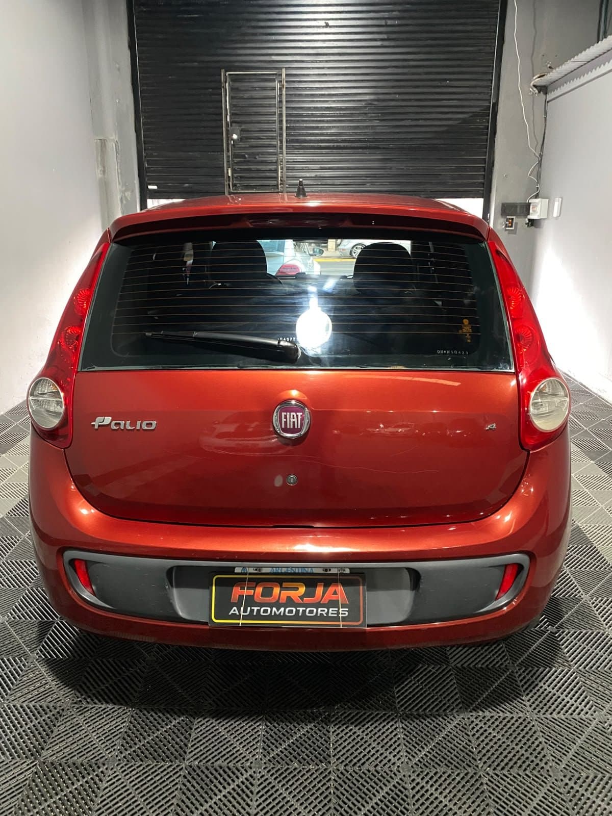 Fiat Palio rojo visto de atrás, en el showroom