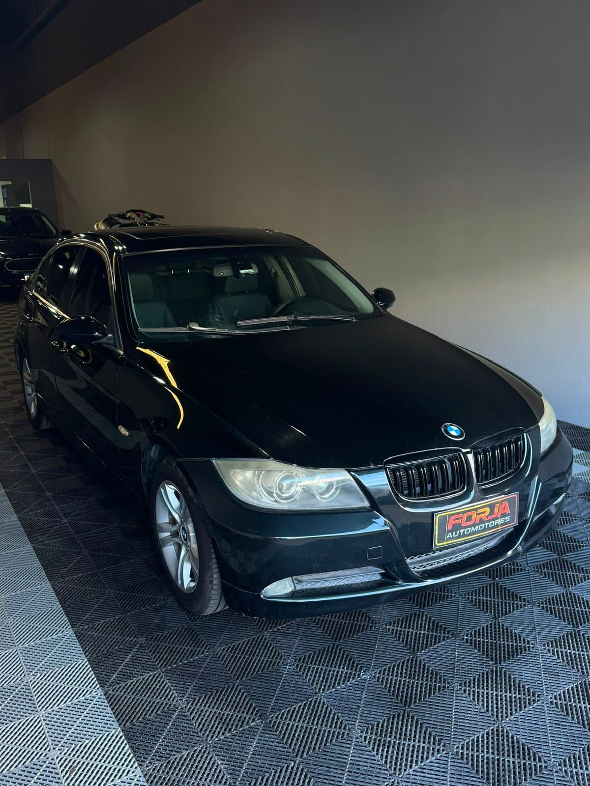 BMW 328i negro, tres cuartos de frente, en el showroom de Forja